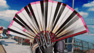 a person is holding a fan in front of their face with a blue sky in the background