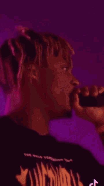 a man with dreadlocks is wearing a black shirt with a tiger print on it .
