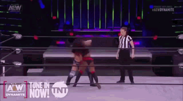 two women are wrestling in a wrestling ring with a referee .