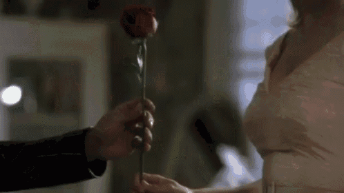 a man is giving a rose to a woman in a white dress .