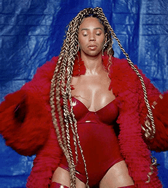 a woman with braids is wearing a red bodysuit and a red coat