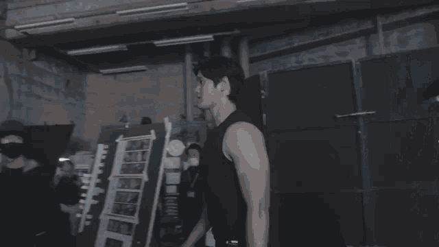 a man in a black tank top stands in front of a camera
