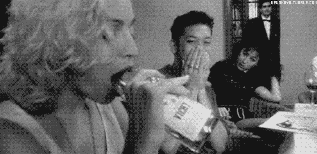 a black and white photo of a woman drinking from a bottle that says vodka