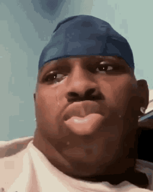 a man with a blue headband on his head is crying with a tear coming out of his mouth .