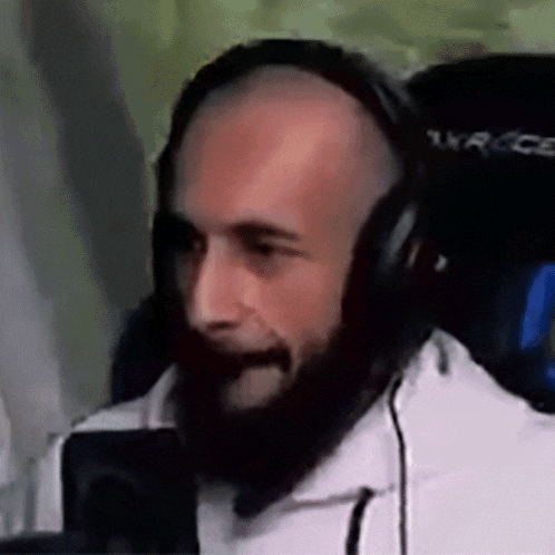 a bald man with a beard wearing headphones is sitting in a chair .