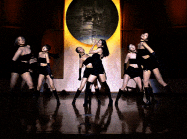 a group of women are standing on a stage in front of a painting