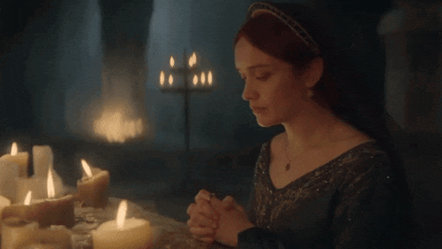 a woman with red hair sits at a table with candles lit