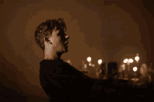 a man in a dark room with candles on the table