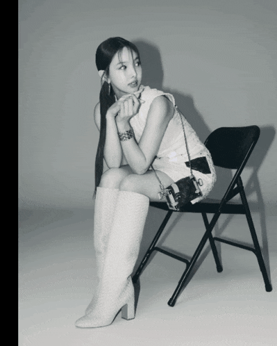 a woman is sitting on a folding chair with her legs crossed