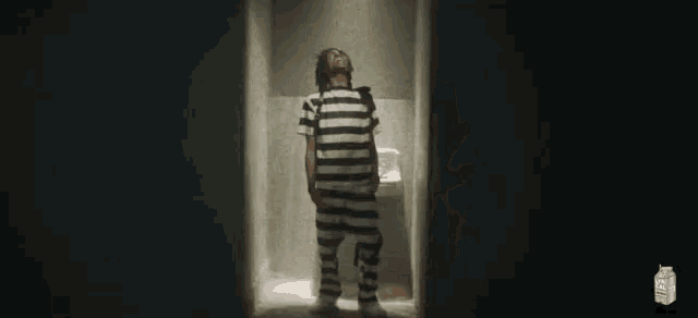 a man in a striped shirt is standing in a hallway with a carton of lysol juice behind him