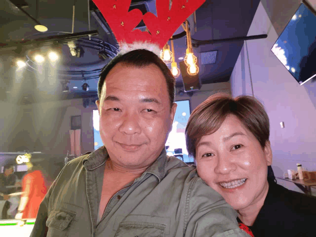 a man and a woman pose for a picture with a santa hat on