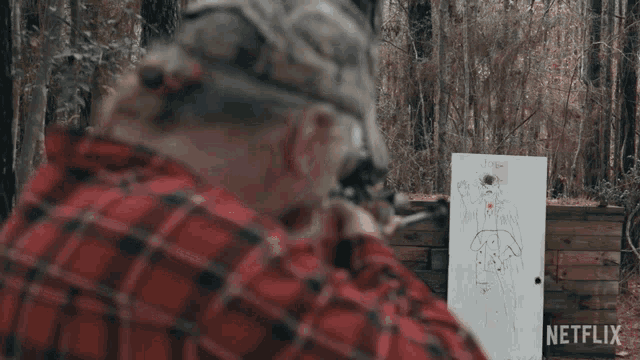 a man in a plaid shirt shoots a rifle at a target that says netflix