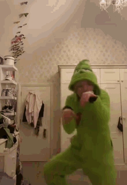 a person in a green costume is dancing in a room .