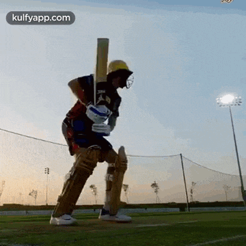 a man is holding a cricket bat on a field .