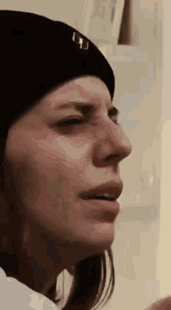 a close up of a woman 's face wearing a black beanie .