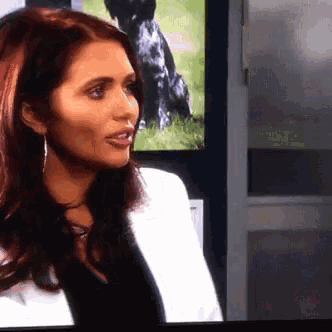 a woman in a white jacket is talking on a television screen