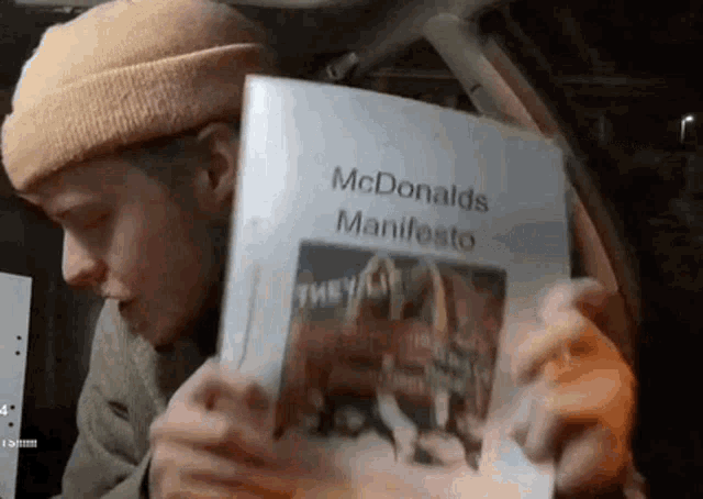 a man in a hat is holding a mcdonald 's manifesto .