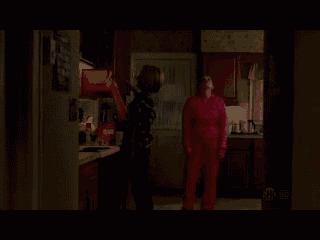 a woman in a pink sweater is standing in a kitchen