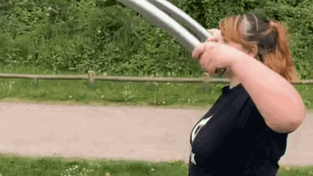 a woman is holding a sword in front of her face in a field .