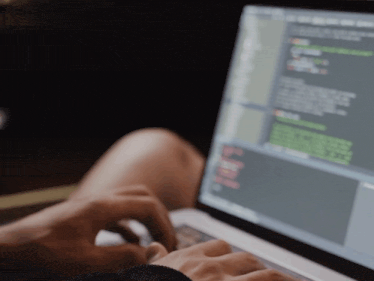 a person is typing on a laptop computer with a blurred background