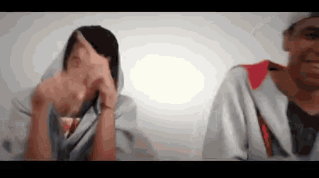 a man and a woman covering their faces with their hands .