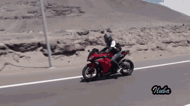 a person is riding a red motorcycle on a road with the word nibba on the bottom left