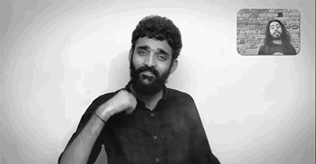 a black and white photo of a man with a beard talking to another man on a video call .