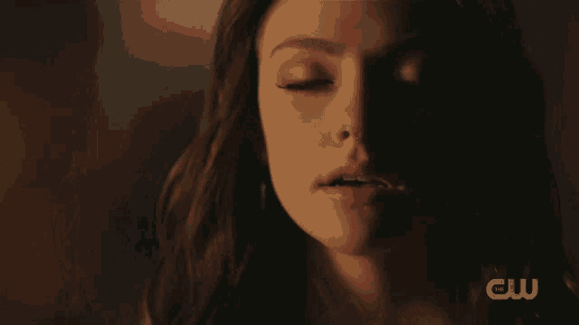a close up of a woman 's face with a cw logo behind her
