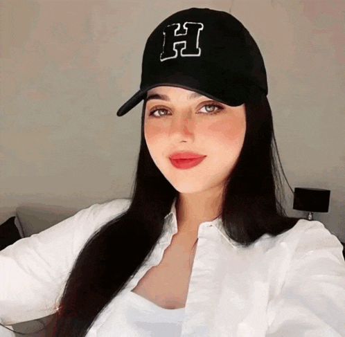 a woman is wearing a black hat with the letter h on it