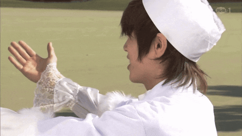 a man in a chef 's hat and white gloves waves his hand