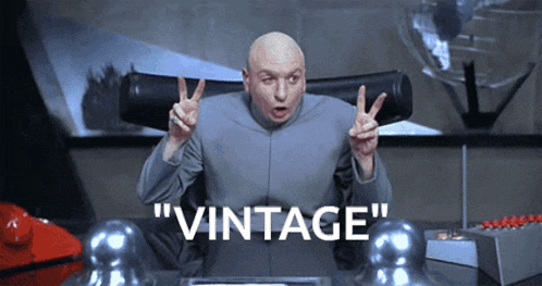 a bald man is giving a peace sign and the word vintage is on the screen behind him