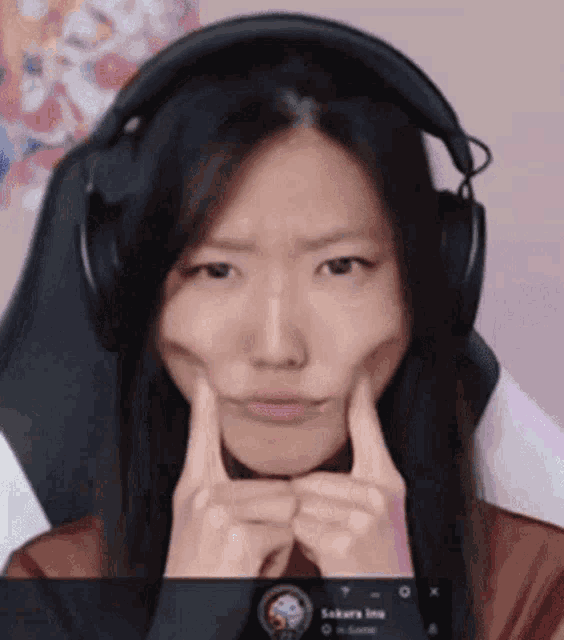 a woman wearing headphones is making a face with her hands .