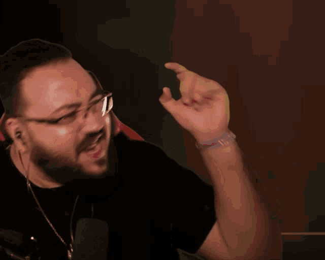 a man wearing glasses and a black shirt holds his fist up