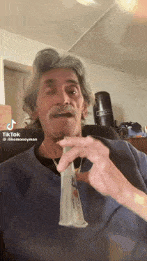 a man with gray hair and a beard is holding a condom in his hand .