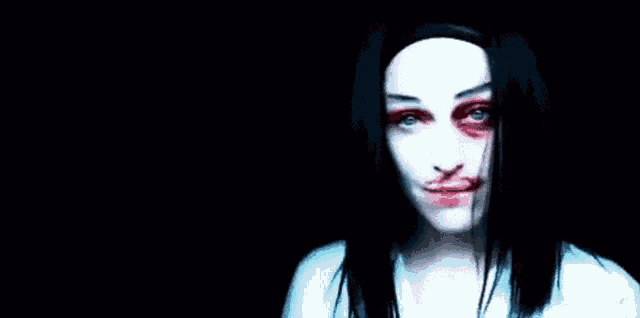 a woman with blood on her face and a black eye is smiling in the dark .