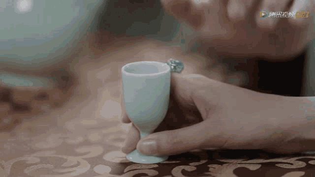 a person is holding a small cup with a ring on it