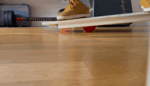 a person 's foot is on a balance board with a red ball