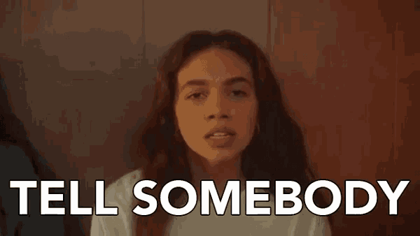 a woman says tell somebody in front of a brown wall