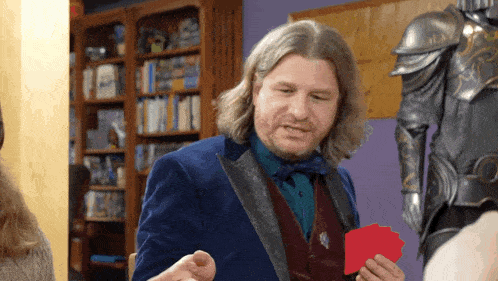 a man in a blue suit holds a red card