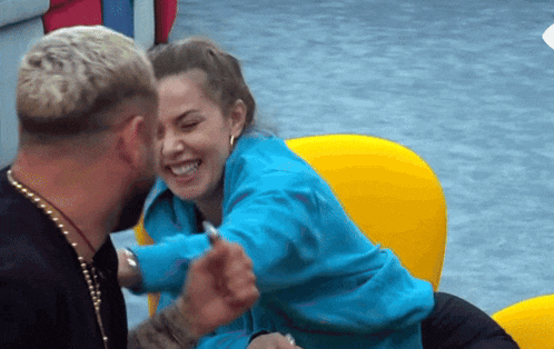 a man and a woman are sitting on a yellow chair and laughing