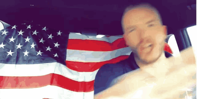 a man in a car with an american flag in the back