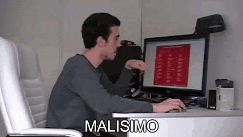a man is sitting at a desk in front of a computer and the word malissimo is written on the screen