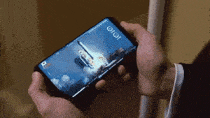 a person is holding a cell phone with a picture of a space shuttle launch on the screen .