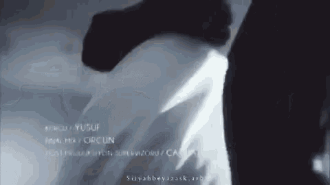 a man in a white shirt is standing in a dark room .