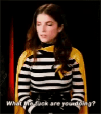 a woman wearing a striped shirt and a yellow cape says what the fuck are you doing .
