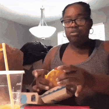 a woman sitting at a table with a coca cola cup