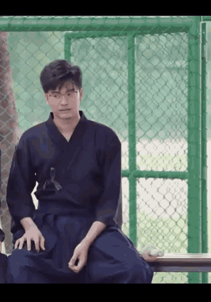 a man in a karate uniform sits on a bench