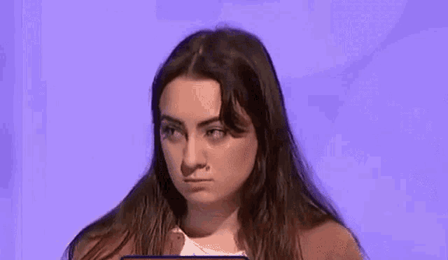 a woman is holding her hand to her forehead while making a funny face .
