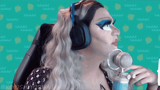 a woman wearing headphones holds a microphone in front of a green background