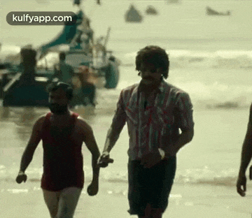 three men are walking on a beach holding hands .